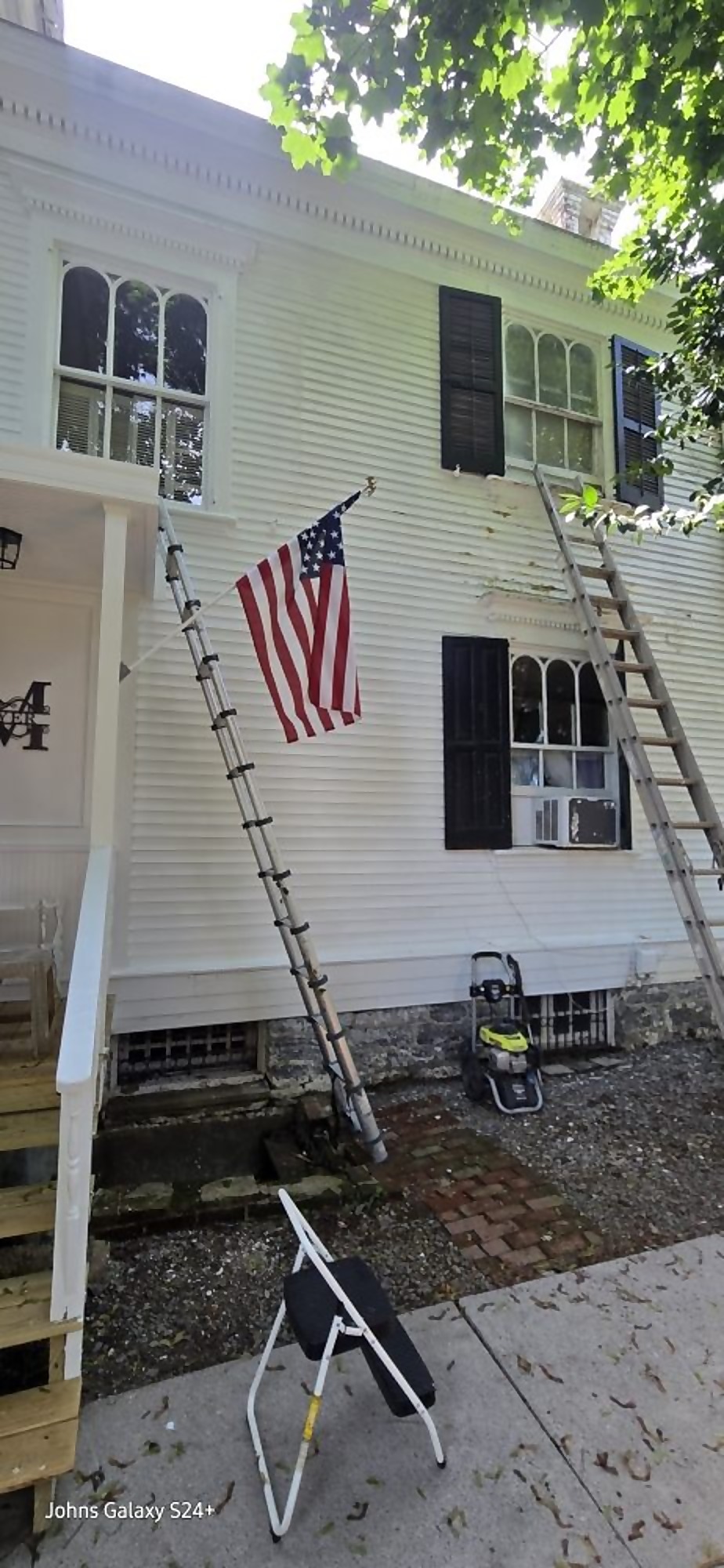 Pro One crew ladder set for exterior painting on a home flying a US flag