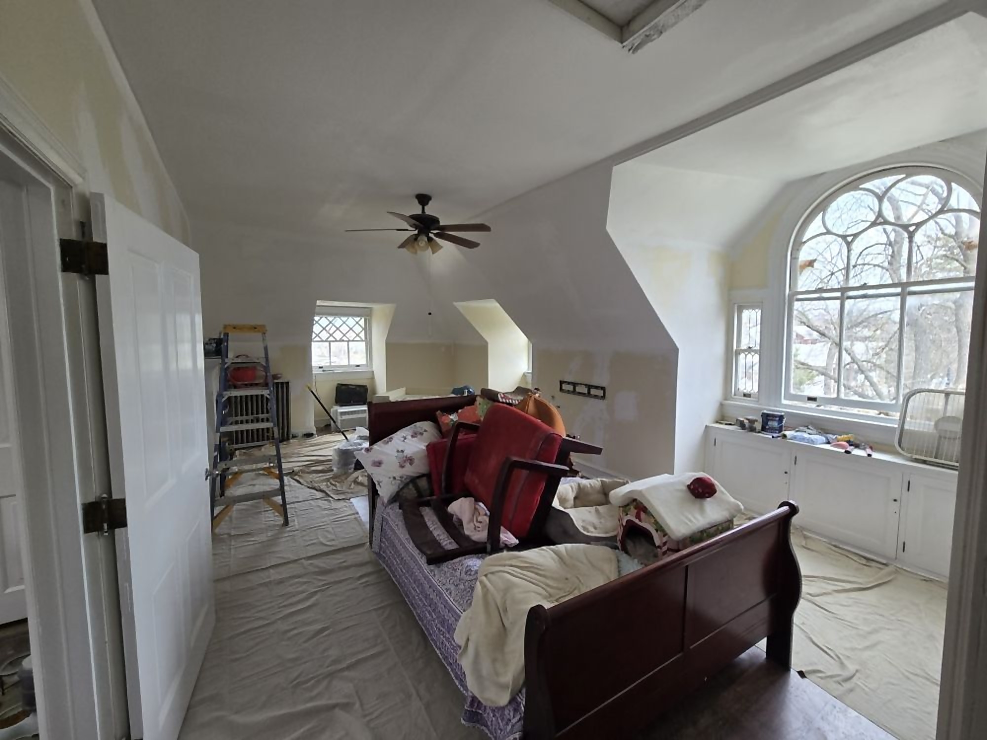 Upstairs bedroom mid-renovation with protected furniture and fresh paint
