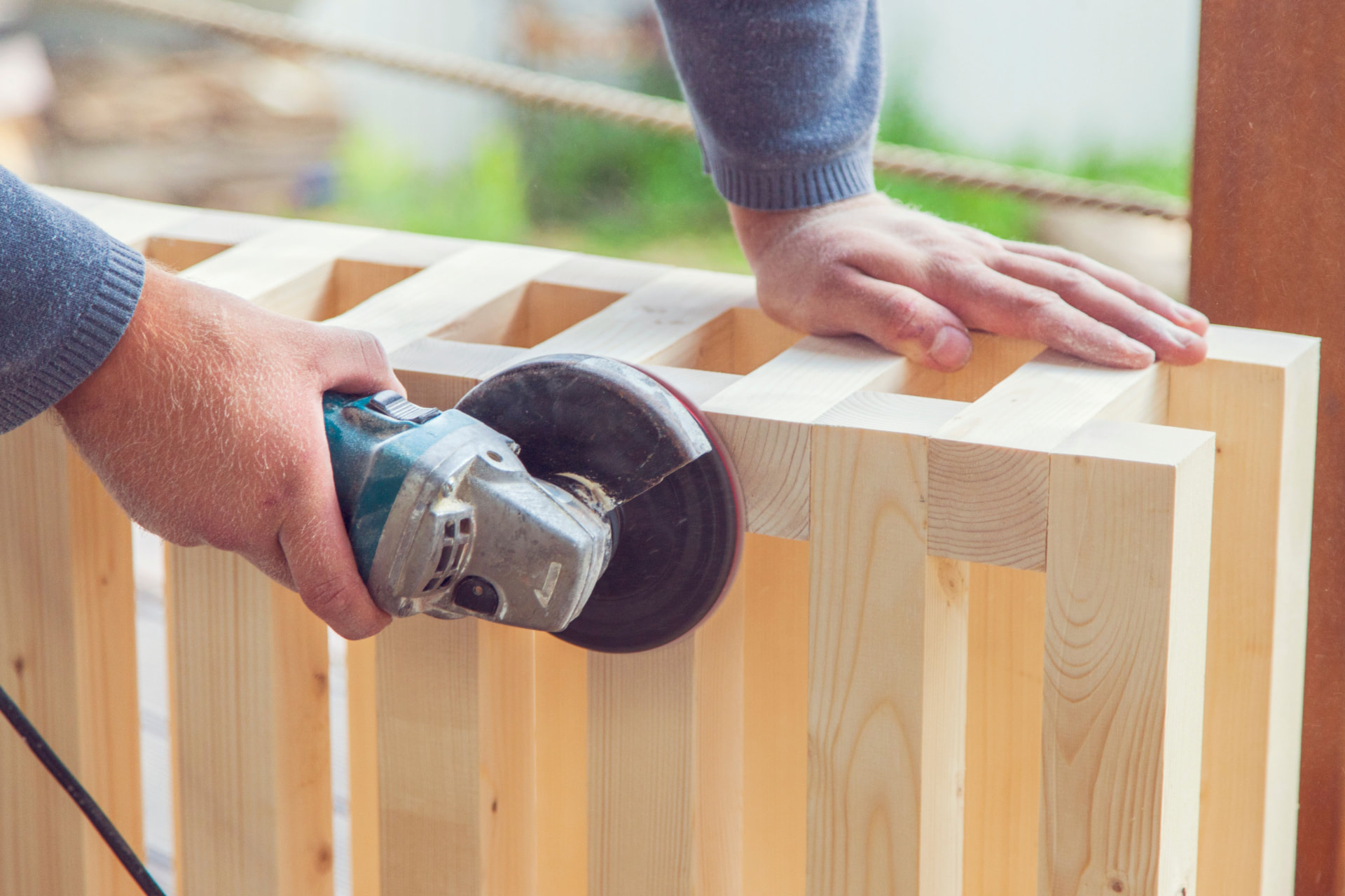 Carpenter sanding a freshly built cedar deck panel on a Pro One jobsite