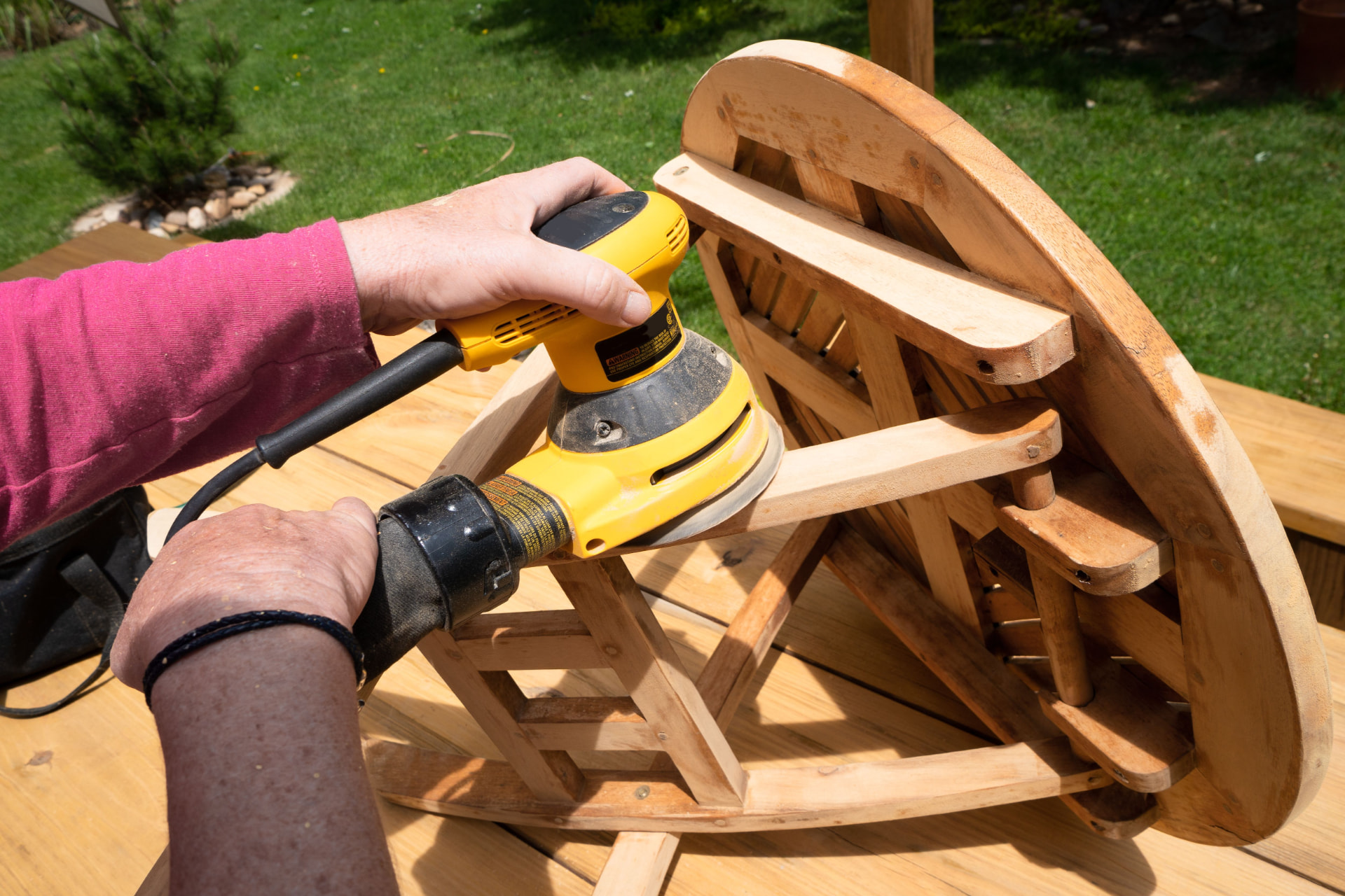 Orbital sander smoothing a wooden table top during a refinishing job